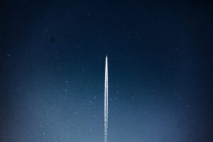 Vapour trail rising into a blue sky